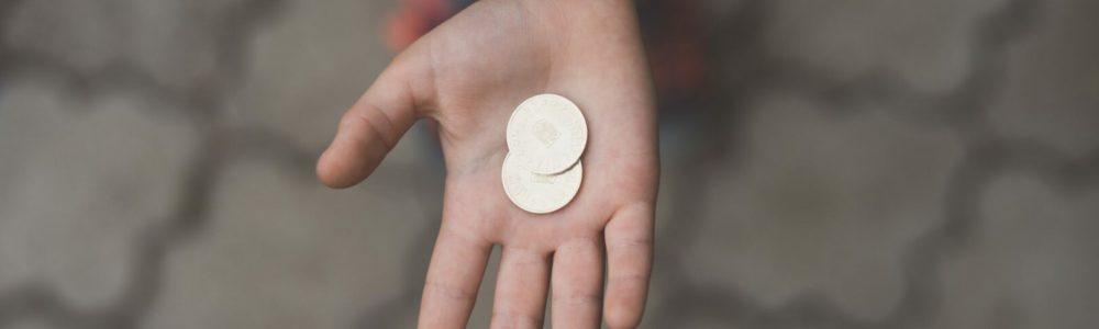 Für Kinder Geld im Alltag sichtbar machen.Kinderhand mit zwei Münzen.